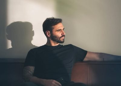 Jake Kramer, co-owner of ARTILLERY, in a sunlit portrait on a leather sofa.